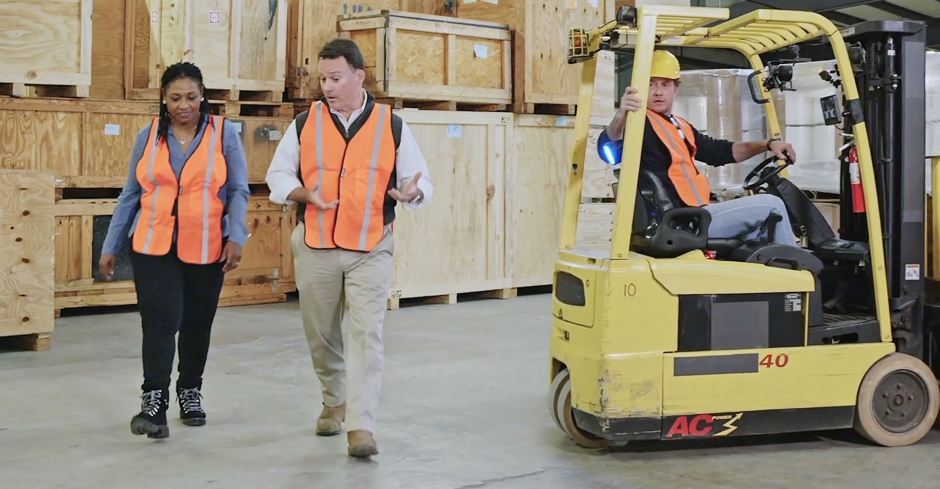 a forklift operator is alerted to two pedestrians walking behind him